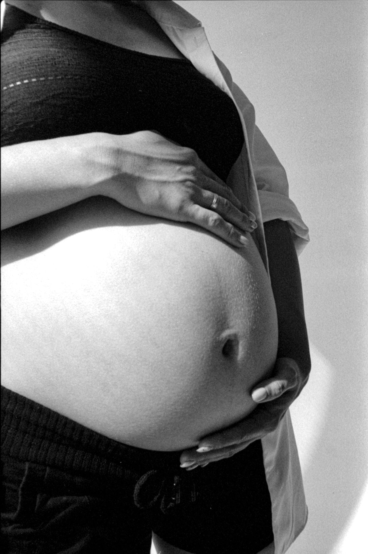 Pregnant woman cradling her bump at five weeks pregnant