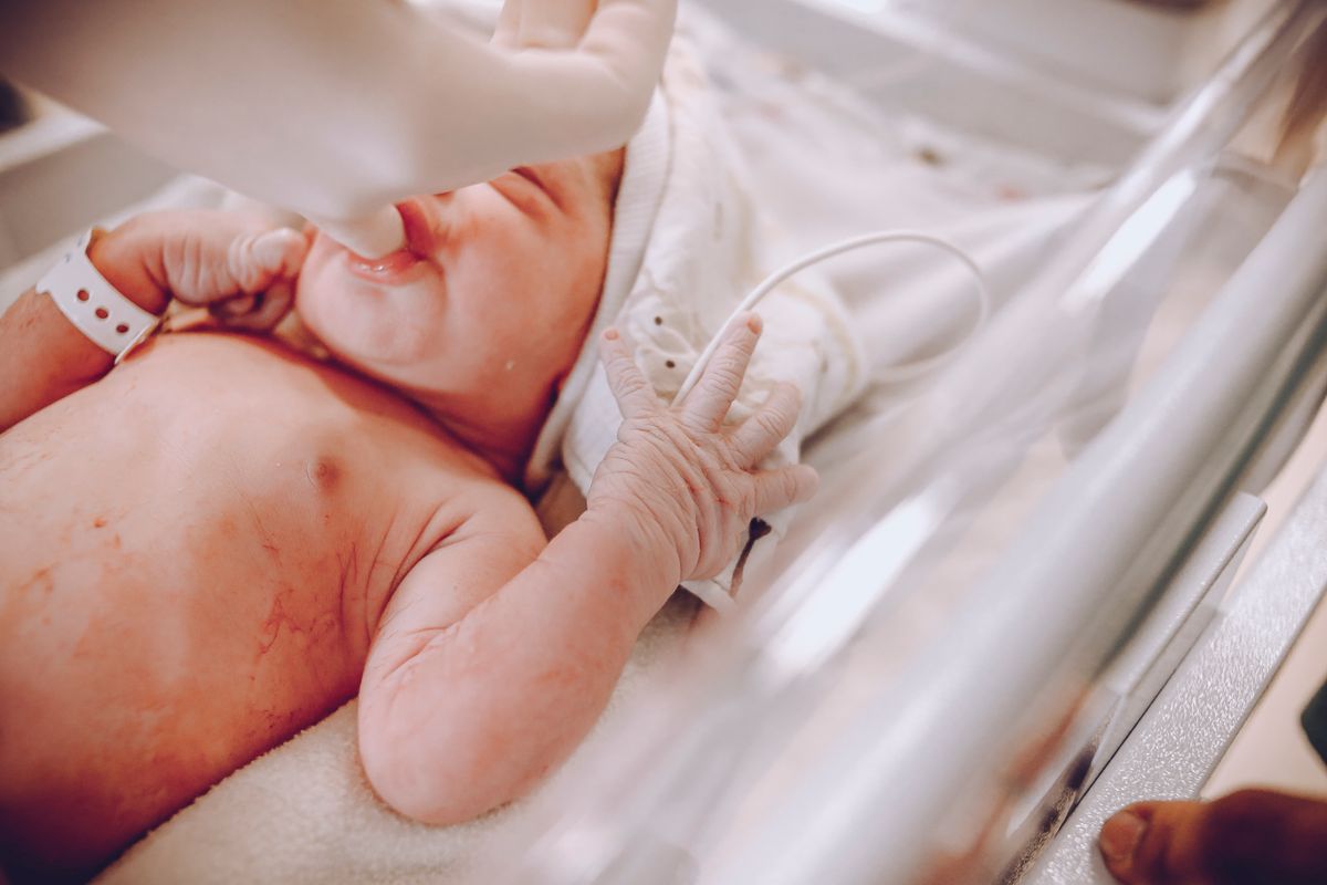 Newborn baby in hospital shortly after birth being held by mother