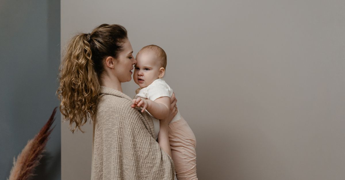 A mother lovingly holds her baby in a serene home interior, exuding warmth and care.