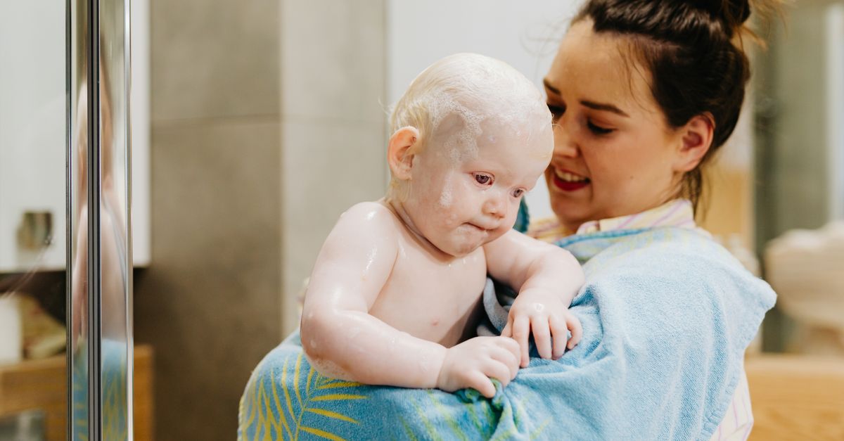 A mother lovingly holds her baby wrapped in a towel after bath time, creating a warm and tender moment.