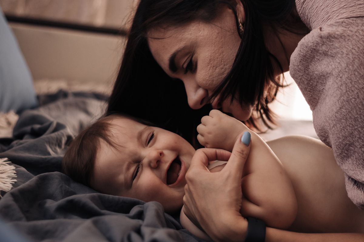 Mother face to face with her laughing baby, chatting and encouraging early speech