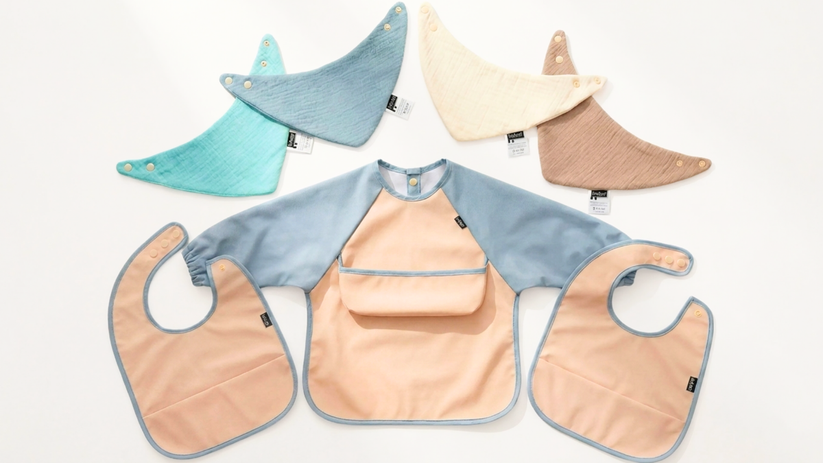 Baby Blue bib-set contents arranged flat: four muslin bibs, two feeding bibs and one coverall