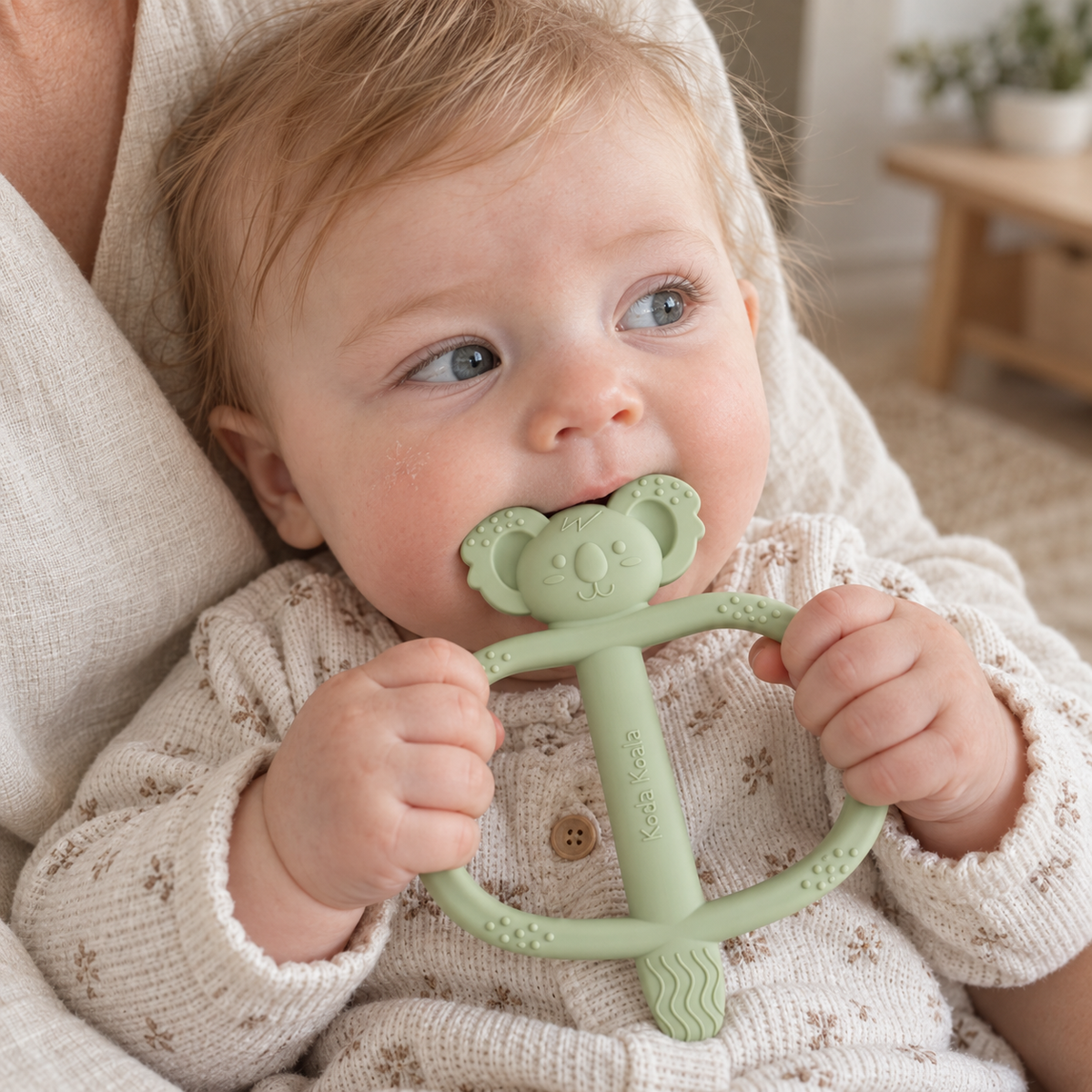 Baby holding and chewing a green Koda Koala Bitey teether