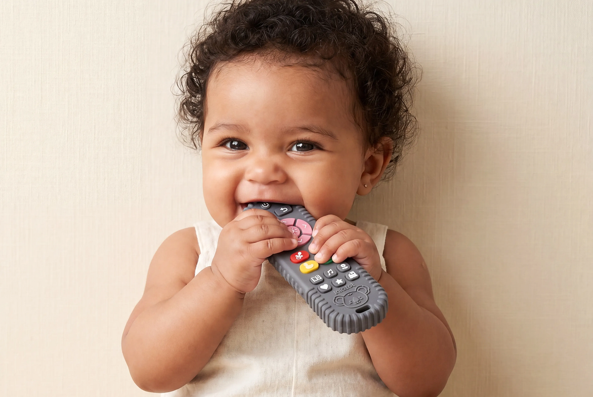 Baby chewing an Infatot remote-shaped teether with raised colourful buttons