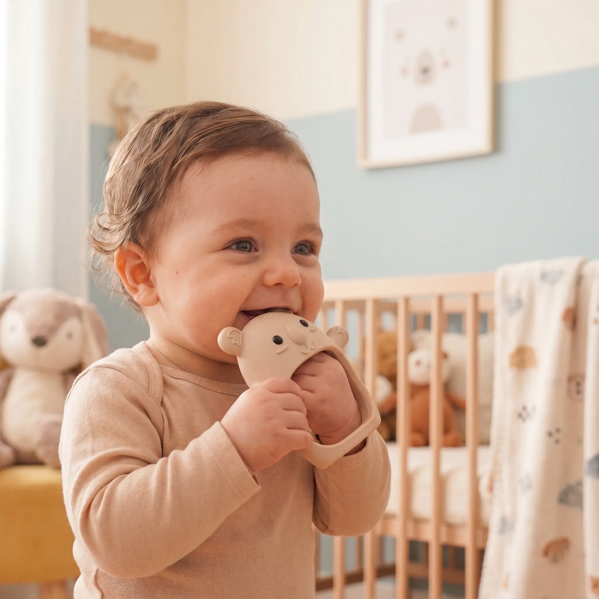 Baby holding a cream Koda Koala teething mitten in a nursery