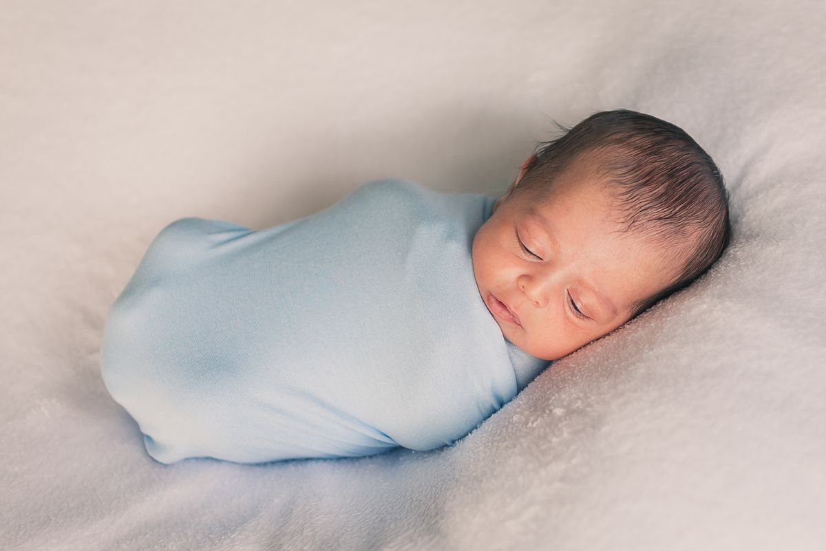 Newborn baby swaddled snugly in soft wrap