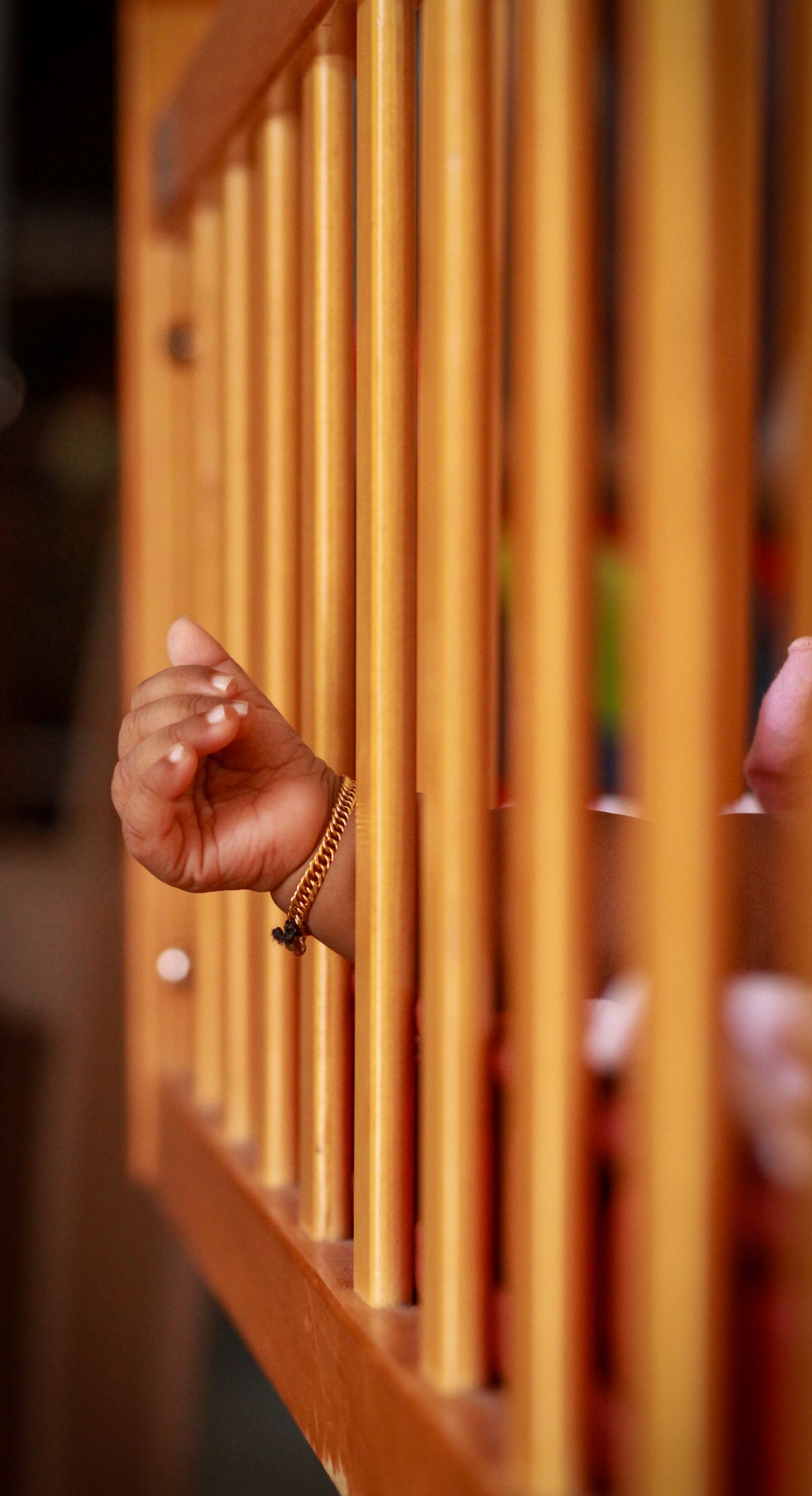 Baby hand resting in a wooden crib — safe sleep for babies