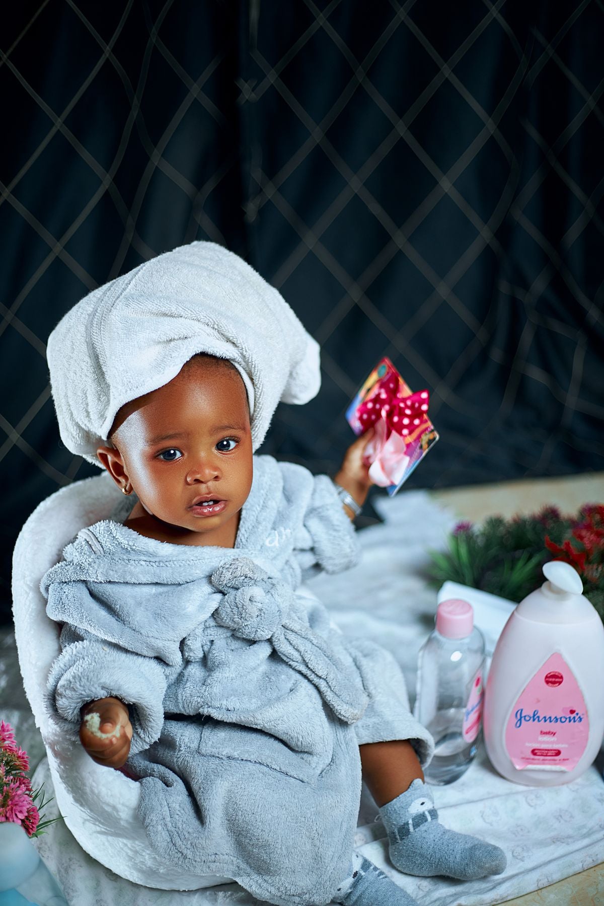 Baby with soft skin in bathrobe with skincare products