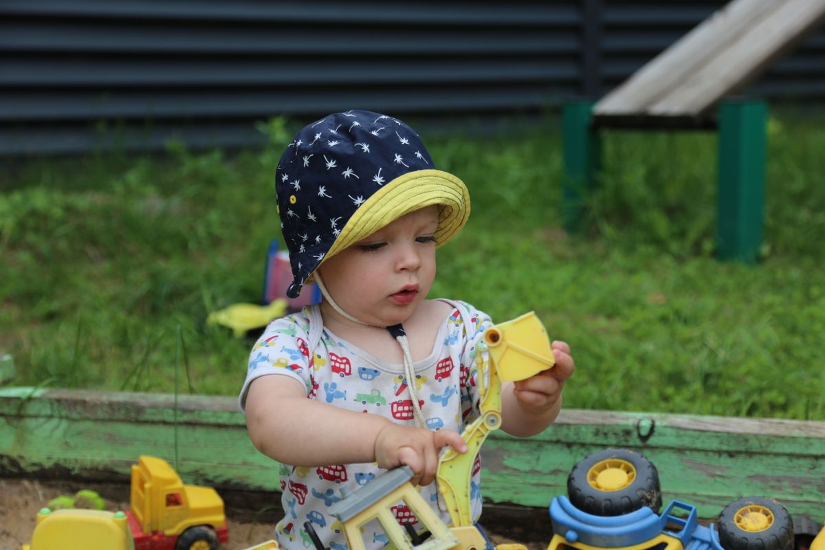 Baby in a sun hat playing in the shade on a hot summer day