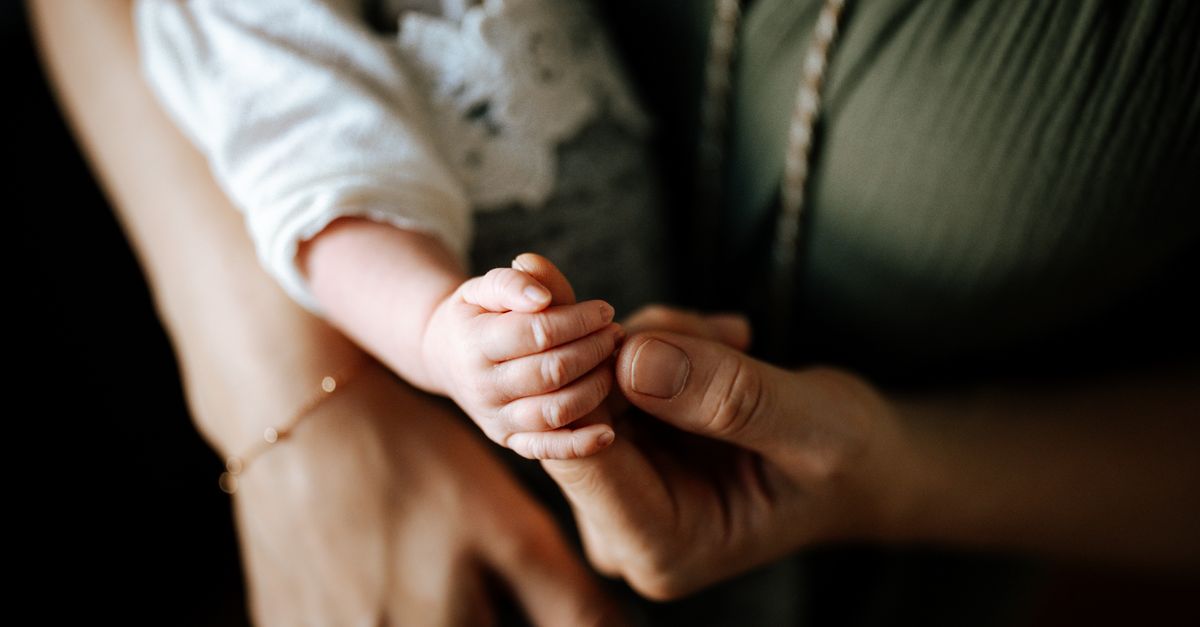 Close-up of a mother holding her baby's hand, capturing a tender and intimate moment.