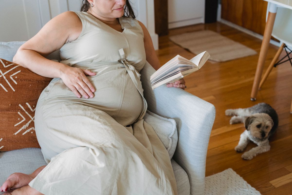 Pregnant woman reading a book and preparing for her baby