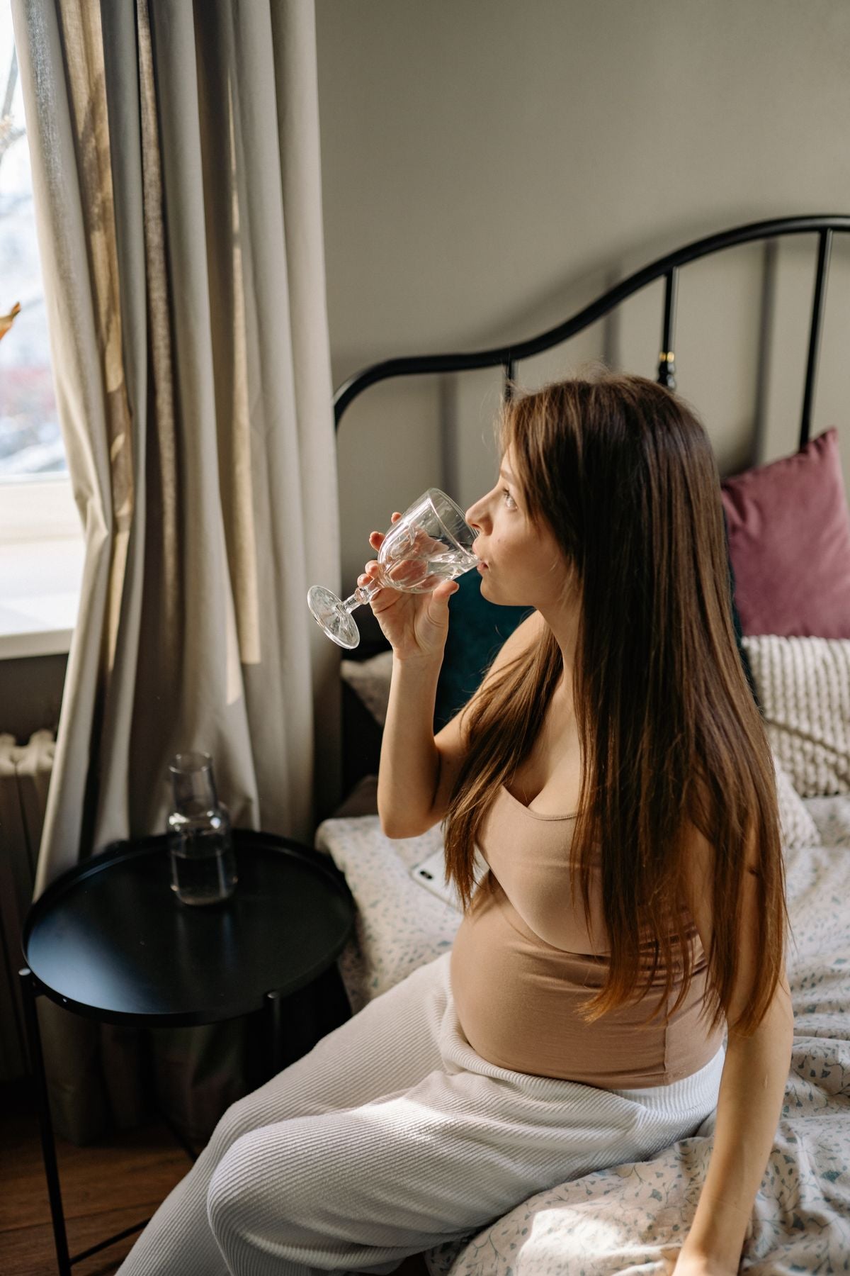 Pregnant woman staying hydrated with water during third trimester