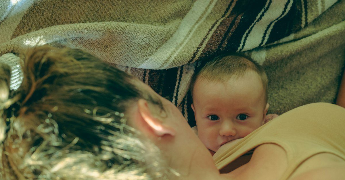 A woman holding a baby under a blanket