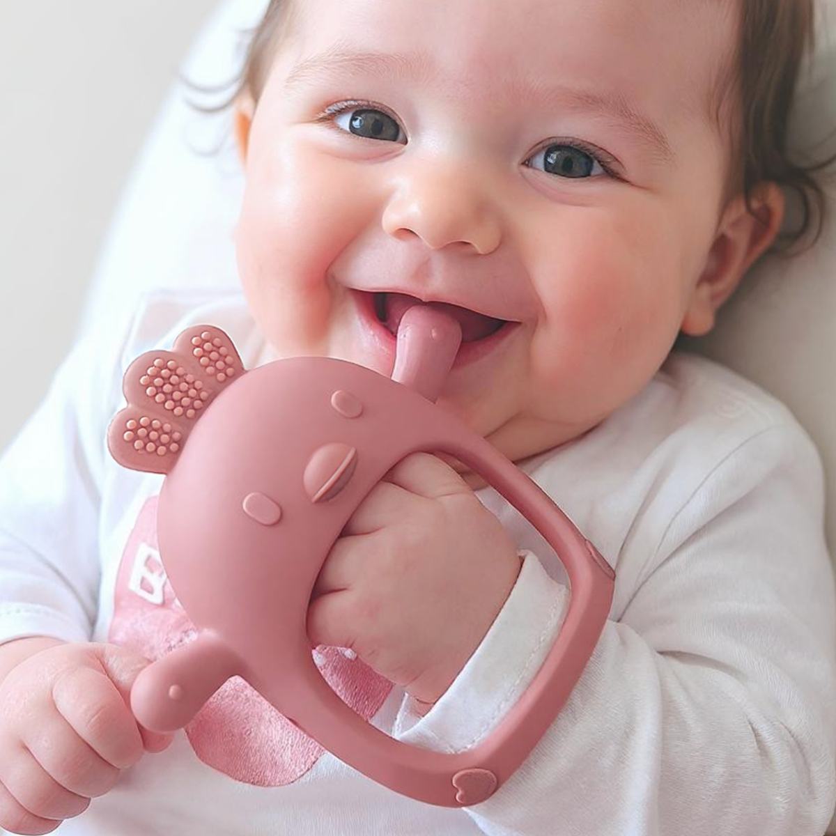 Smiling baby chewing the Infatot Chicken Teething Mitten in Plum