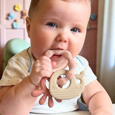 Baby holding and chewing a pale pink MultiTexture Sea Teether