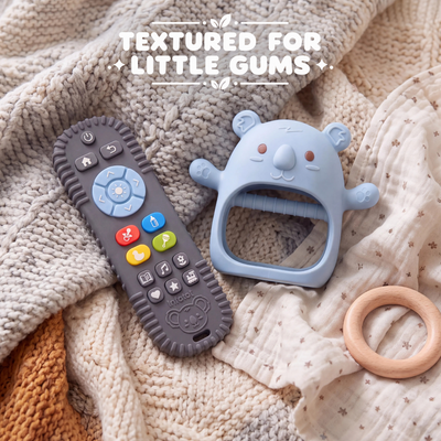 Blue Koda Koala mitten and remote-shaped teether resting on blankets