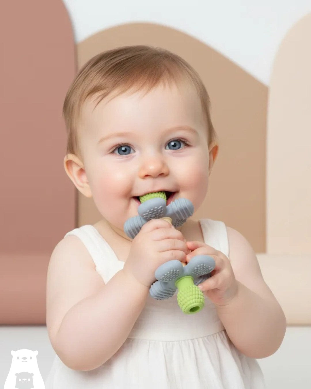 Baby chewing a green and blue Barbell Buddy teether