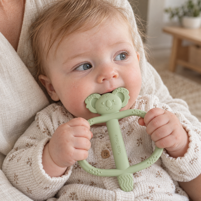 Baby holding and chewing a green Koda Koala Bitey teether