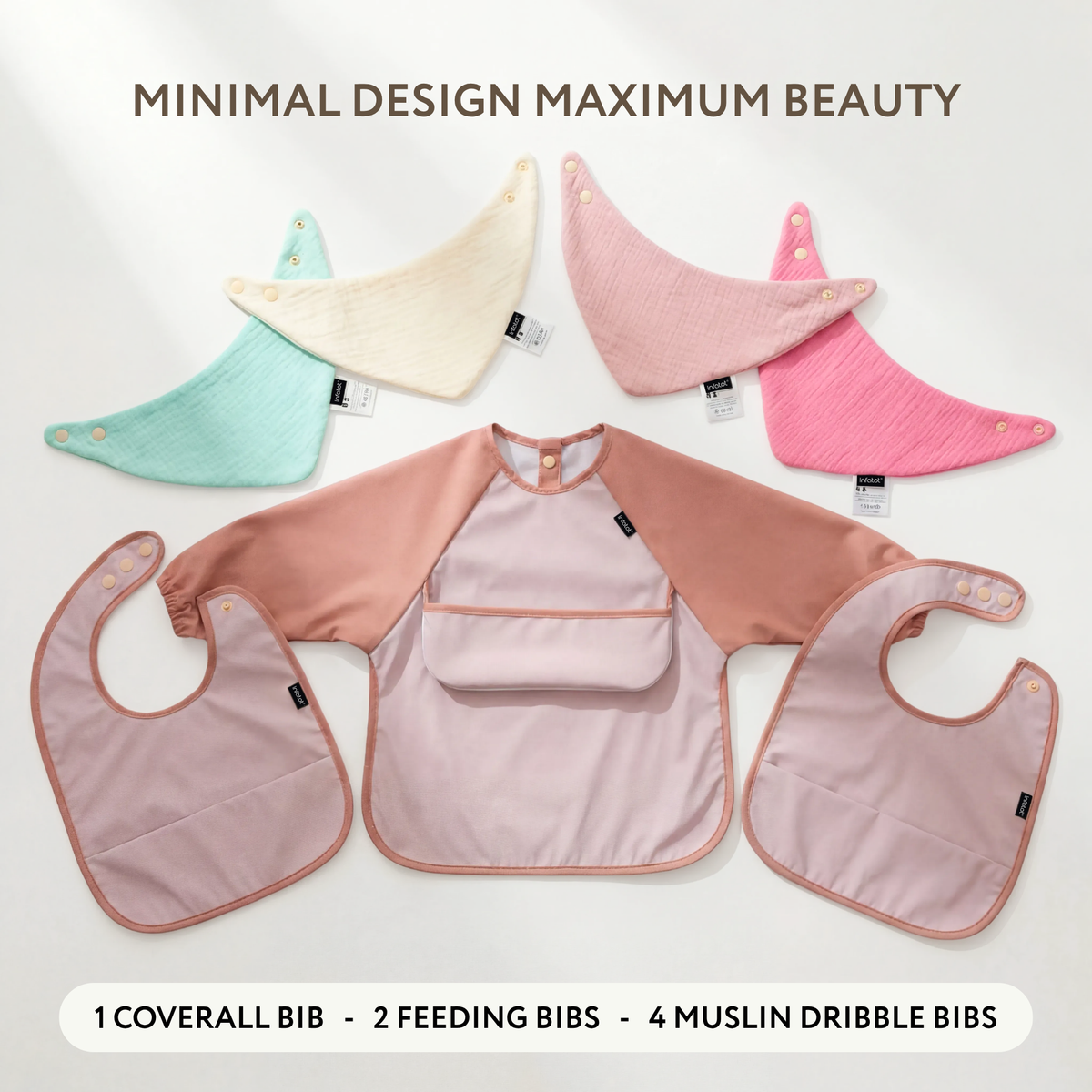 Blush seven-piece bib set arranged to show the coverall, two feeding bibs and four muslin bibs
