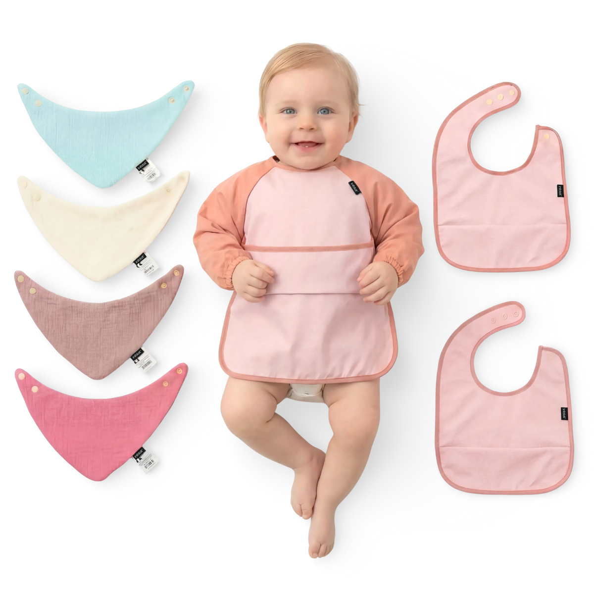 Baby wearing a pink coverall beside four muslin bibs and two pink feeding bibs
