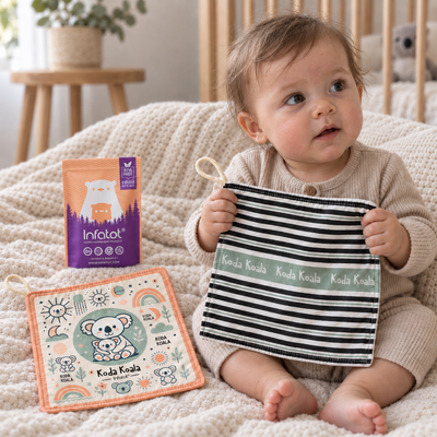 Baby holding a Willow Koda Koala crinkle sheet with striped fabric and green edging