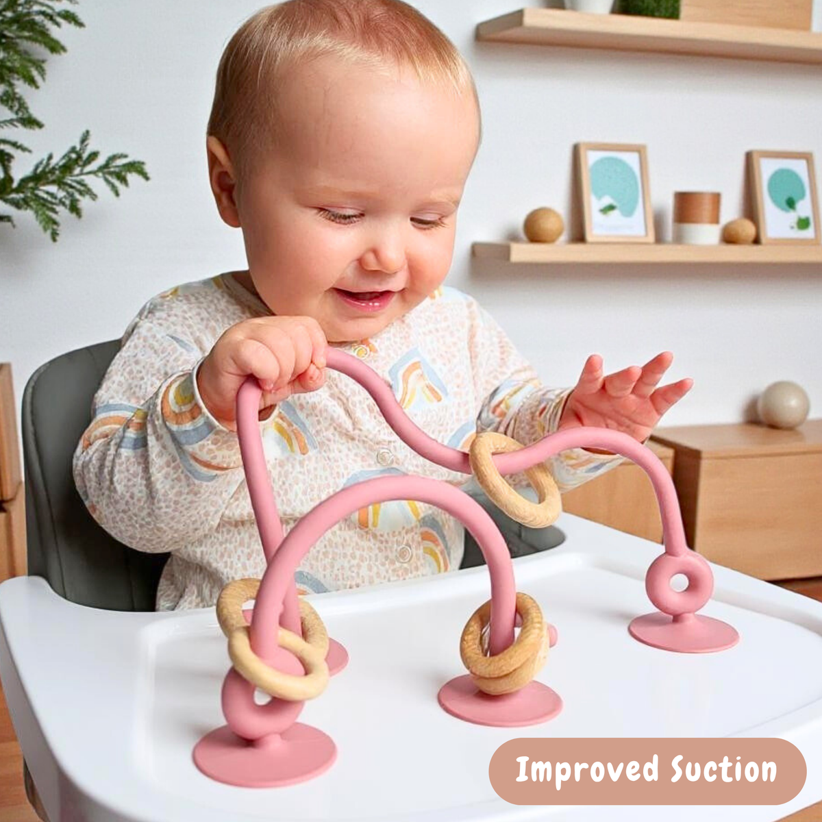 Baby playing with an Infatot suction toy attached to a highchair tray