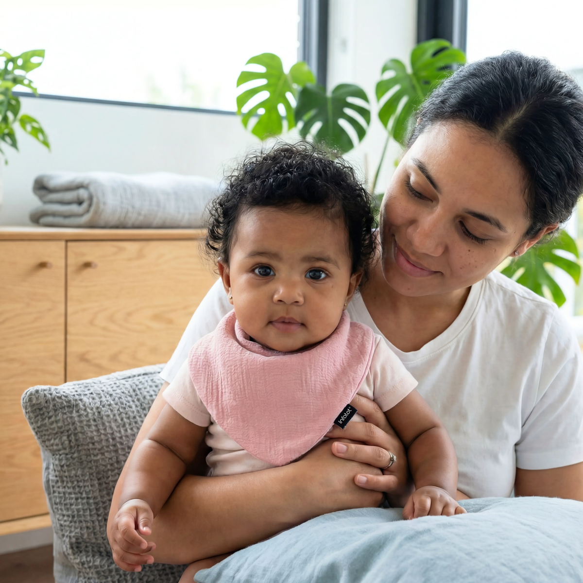 Parent holding a baby wearing a pink muslin dribble bib