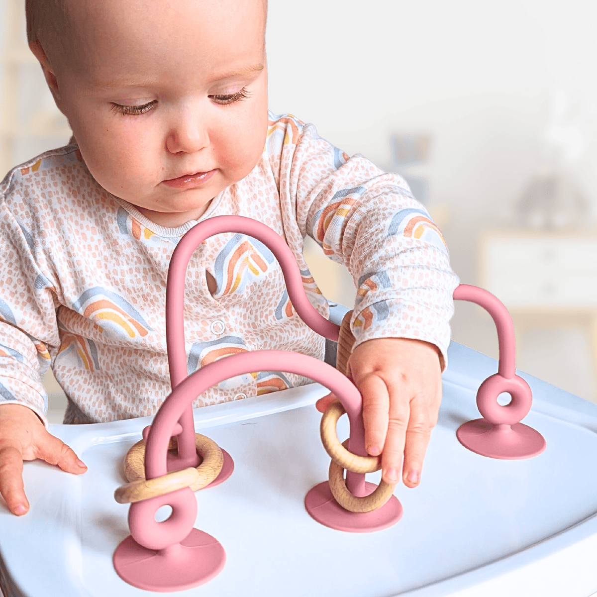 Baby playing with the Infatot Suction Toy attached to a highchair tray